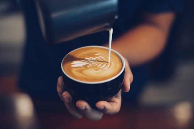 Pouring milk into coffee and creating latte art 