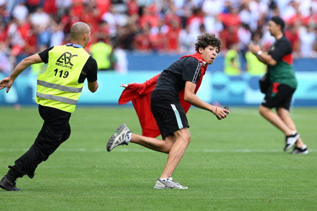 A pitch invader is chased by a steward.