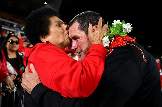 Tonga's head coach Kristian Woolf celebrates with a fan triumphing over New Zealand in the Pacific Championships.