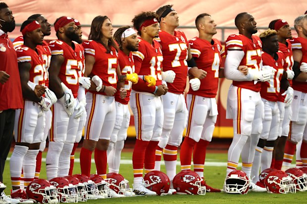 Members of the Kansas City Chiefs stand united with locked arms.