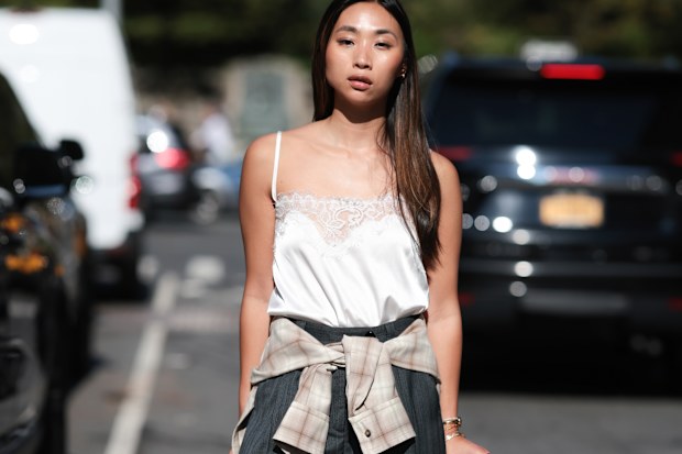 New York Fashion Week guest wears a white satin camisole with dark gray wide-leg pants, September 2025