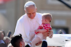 Pope Leo XIV holds a baby as he arrives ahead of the Inauguration Mass 