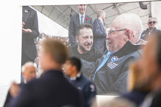 Shown in a big screen, Ukrainian President Volodymyr Zelenskyy greets US World War II veterans as they arrive for an international ceremony to mark the 80th anniversary of D-Day at Omaha Beach in Saint-Laurent-sur-Mer, Normandy, France, Thursday, June 6, 2024.