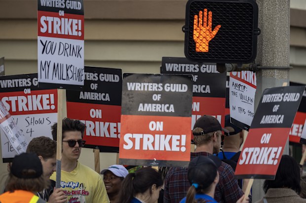 LOS ANGELES, CA - MAY 04: People picket outside of Paramount Pictures studios during the Hollywood writers strike on May 4, 2023 in Los Angeles, California. Scripted TV series, late-night talk shows, film and streaming productions are being interrupted by the Writers Guild of America (WGA) strike. In 2007 and 2008, a WGA strike shut down Hollywood productions for 100 days, costing the local economy between $2 billion and $3 billion. (Photo by David McNew/Getty Images)
