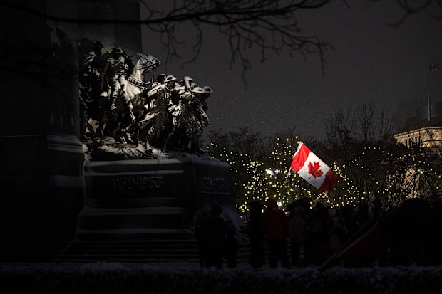 Protesters fly the Canadian flag as they stand by the Tomb of the Unknown Soldier at the National War Memorial on the 21st day of a protest against COVID-19 measures that has grown into a broader anti-government protest, on Thursday, Feb. 17, 2022, in Ottawa.