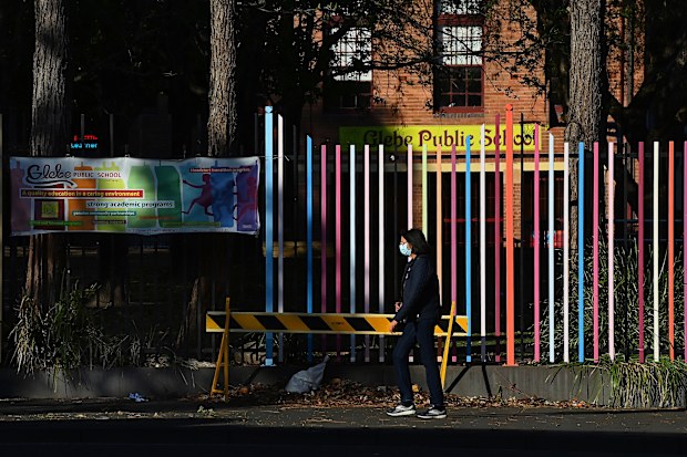 A woman wearing a face mask walks past Glebe Public School during the city wide COVID-19 lockdown. Glebe, NSW. 22nd September, 2021. Photo: Kate Geraghty