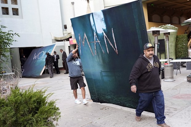 Crew members carry out signs for the new film "Wolf Man" after the premiere was cancelled