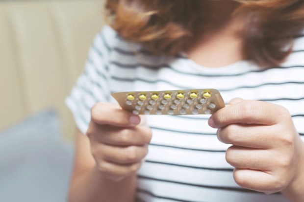 Woman holding birth control pills