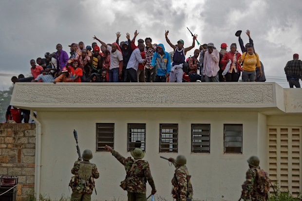 Police order supporters of President Uhuru Kenyatta off a roof during clashes at his inauguration ceremony after they tried to storm through gates to get in and were tear-gassed, at Kasarani stadium in Nairobi, Kenya (AP Photo/Ben Curtis)