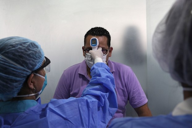 A man wearing a mask as a precautionary measure against the spread of the new coronavirus gets his temperature taken.