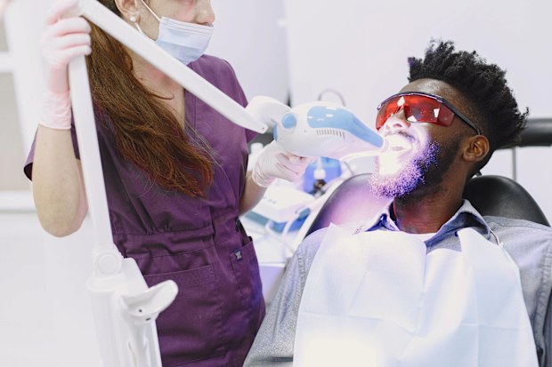 Stock photo of a man having his teeth whitened at the dentist.