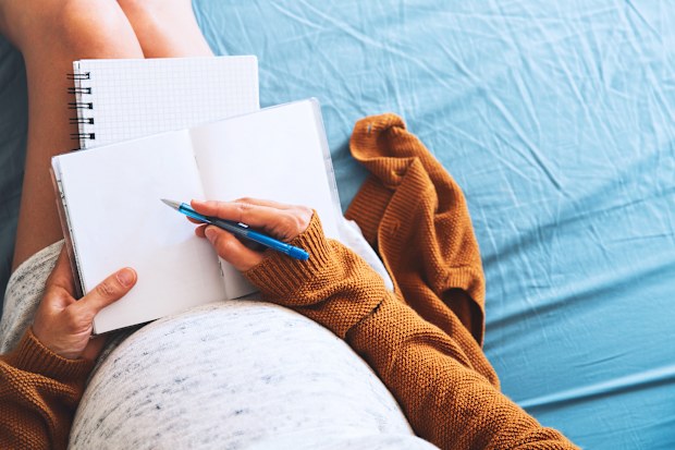 Pregnant woman makes notes and looking at medical documents. Concept of pregnancy, health care, gynecology, medicine. Mother waiting of baby.