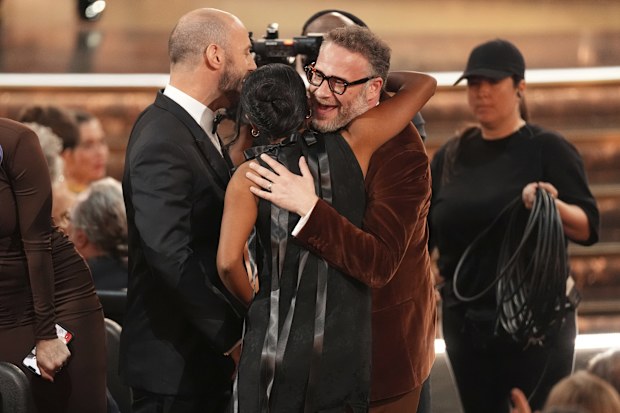 Evan Goldberg, from left, Frida Perez, and Seth Rogen embrace after winning the award for outstanding writing for a comedy series for "The Studio" during the 77th Primetime Emmy Awards on Sunday, Sept. 14, 2025, at the Peacock Theater in Los Angeles.  