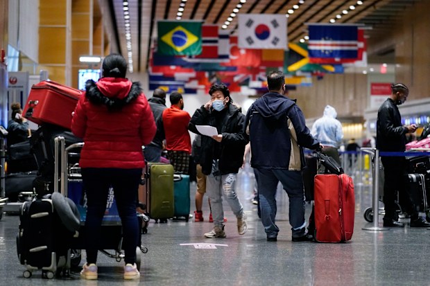 Travellers wait in line to check in for flights at Logan Airport, Tuesday, Dec. 21, 2021, in Boston. 