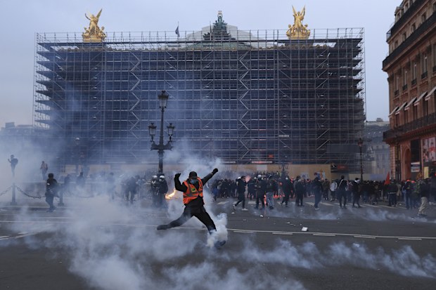 A protester kicks a tear gas canister in front of the Opera at the end of a rally in Paris, Thursday, march 23, 2023. 