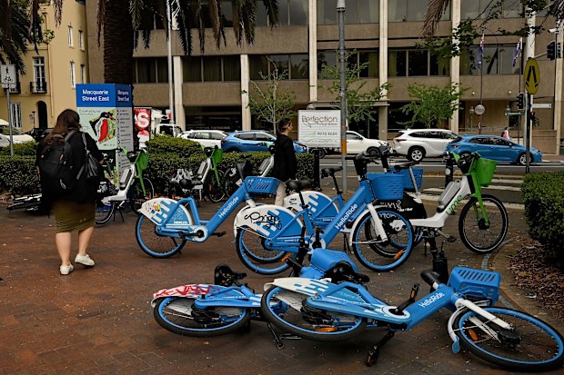 Pedestrians walk past e-bikes near the NSW State Library in Sydney.