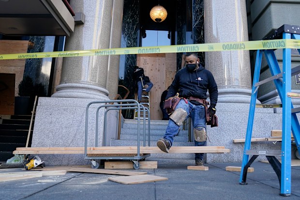 A work crew applies wooden boards to the exterior of The Westin Saint Francis San Francisco on Union Square hotel in San Francisco, Monday, Nov. 2, 2020, ahead of Election Day. (AP Photo/Jeff Chiu)