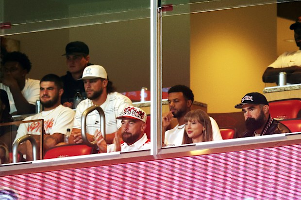 KANSAS CITY, MISSOURI - AUGUST 28:  Travis Kelce #87 of the Kansas City Chiefs, Taylor Swift and Jason Kelce watch during the first half of the game between the Cincinnati Bearcats and the Nebraska Cornhuskers at Arrowhead Stadium on August 28, 2025 in Kansas City, Missouri. (Photo by Jamie Squire/Getty Images)