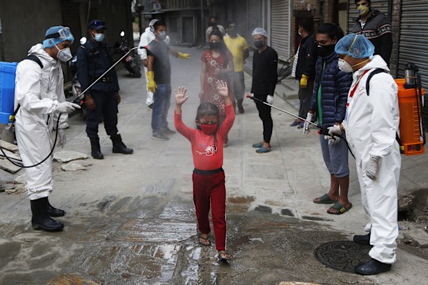 A young Nepalese girl is sprayed with disinfectants as she arrives to get free food distributed by social workers during lockdown to control the spread of the new coronavirus in Kathmandu, Nepal