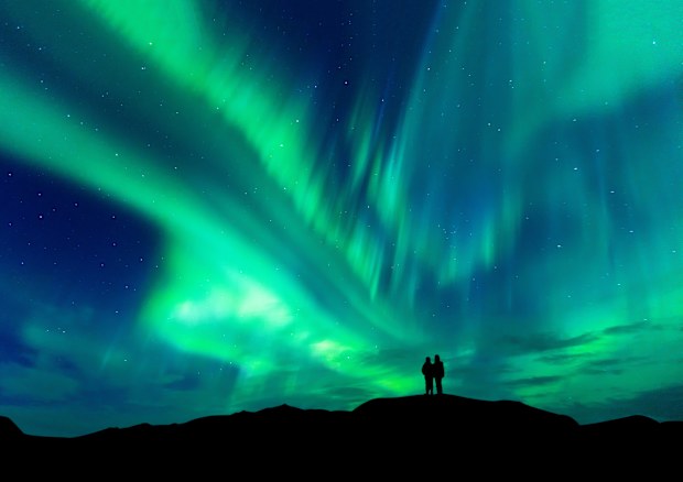 Aurora borealis in Finland with silhouette love romantic couple on the mountain.