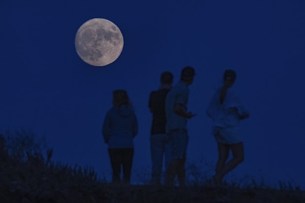 Visitors stop to take pictures of a waxing gibbous moon at 96% illumination at Fort Baker in Sausalito, Calif., on Tuesday, Aug. 29, 2023.