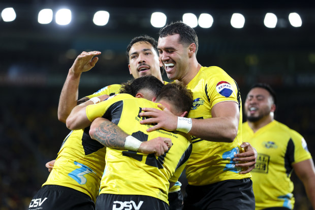 TJ Perenara of the Hurricanes celebrates with teammates after scoring a try.