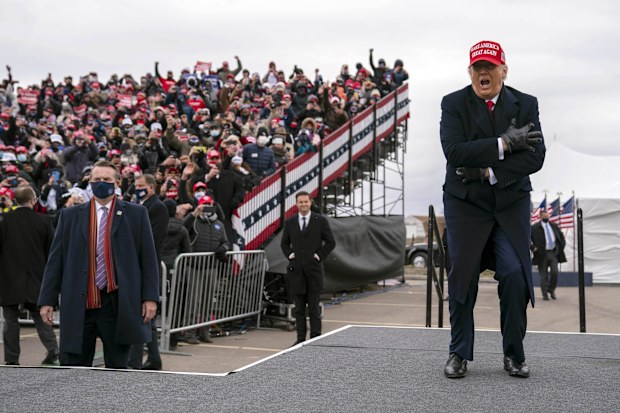 President Donald Trump braces from the cold as he arrives Oakland County International Airport