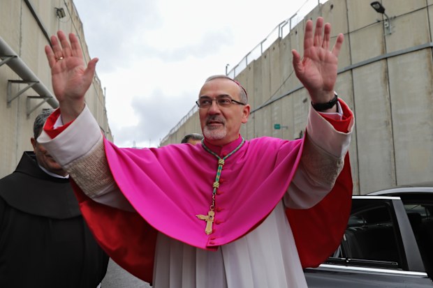 Latin Patriarch Pierbattista Pizzaballa greets worshippers next to the separation wall between the West Bank city of Bethlehem and Jerusalem on his way to the Church of the Nativity in Bethlehem, Friday, Dec. 24, 2021. 