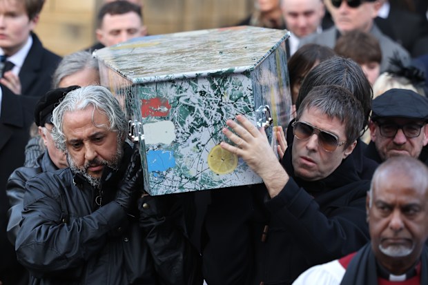 MANCHESTER, ENGLAND - DECEMBER 22:   Liam Gallagher helps carry the coffin out of the funeral of Gary Mounfield, also known as Mani, at Manchester Cathedral on December 22, 2025 in Manchester, England. Mani is know for being the bass guitarist in rock bands The Stone Roses and Primal Scream. He died on November 20, 2025 at the age of 63 after suffering from a long-standing lung condition.  (Photo by Ryan Jenkinson/Getty Images)