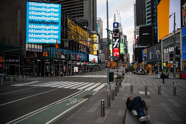 A billboard displaying hashtags concerning COVID-19 hangs over a sparsely populated Times Square, Friday, March 20, 2020, in New York. New York Gov. Andrew Cuomo is ordering all workers in non-essential businesses to stay home and banning gatherings statewide. Only essential businesses can have workers commuting to the job or on the job, Cuomo said of an executive order he will sign Friday. Nonessential gatherings of individuals of any size or for any reason are canceled or postponed. (AP Photo/