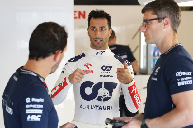 Daniel Ricciardo of Australia talks with the Scuderia AlphaTauri team in the garage during previews at Hungary.