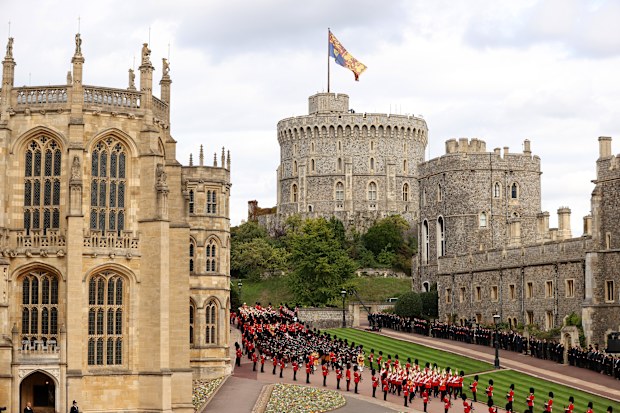 WINDSOR, ENGLAND - SEPTEMBER 19: The coffin of Queen Elizabeth II is carried in The state hearse as it proceeds towards Windsor Castle for The Committal Service for Queen Elizabeth II as the Royal Standard flies above the castle on September 19, 2022 in Windsor, England. The committal service at St George's Chapel, Windsor Castle, took place following the state funeral at Westminster Abbey. A private burial in The King George VI Memorial Chapel followed. Queen Elizabeth II died at Balmoral Castl