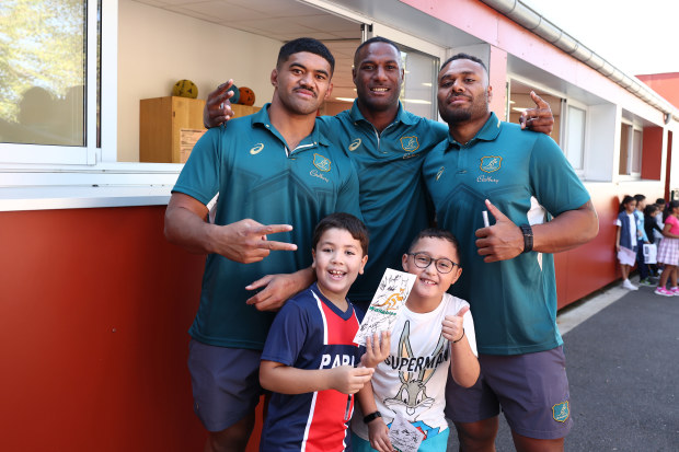 Jordan Uelese (from left), Suli Vunivalu and Samu Kerevi of the Wallabies pose with students during a school visit ahead of the Rugby World Cup match against Fiji.