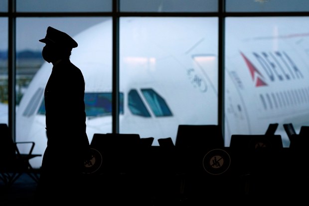 A Delta Airlines pilot wears a face mask to help prevent the spread of the new coronavirus as he walks through a terminal at Hartsfield-Jackson International Airport in Atlanta, Thursday, Feb. 18, 2021. (AP Photo/Charlie Riedel)