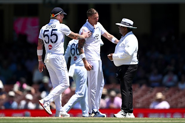 Brydon Carse of England is pulled away by captain Ben Stokes after speaking to umpire Ahsan Raza.