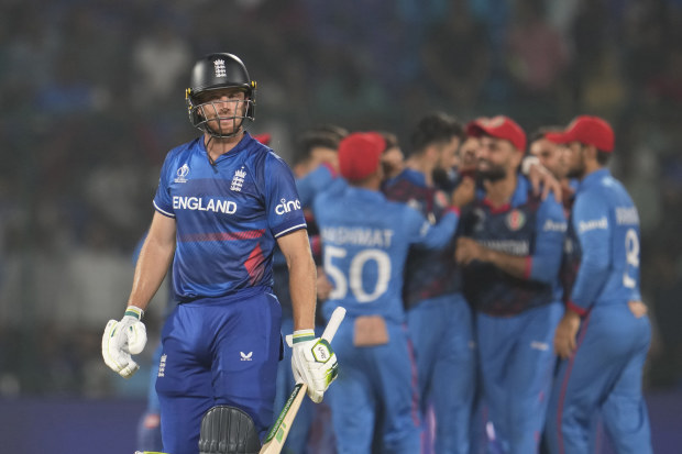 England's captain Jos Butler leaves the ground after losing his wicket as Afghanistan's Naveen-ul-Haq celebrates with teammates.
