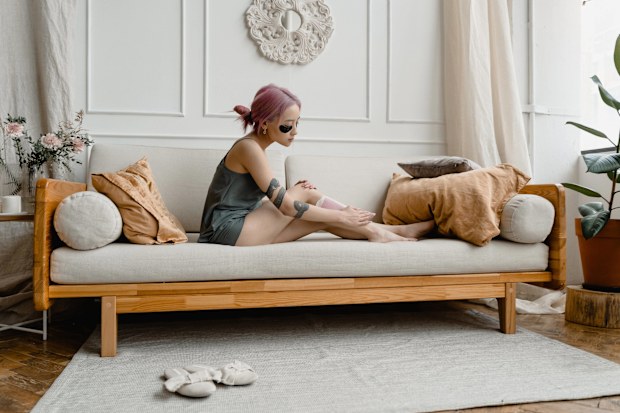Stock photo of a woman waxing her legs at home.