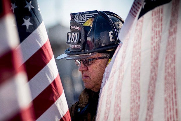 Retired fire engineer Bill Marshall wears his old firefighting gear and carries a flag with the names of all 3,000 people killed in the September 11 attacks as he walks through the Healing Fields at Tempe Beach Park in Tempe, Arizona, USA