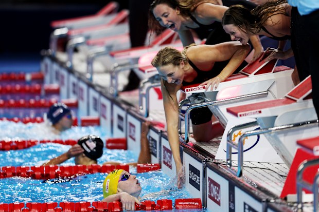 Mollie O'Callaghan is greeted by her relay teammates after completing the anchor leg.