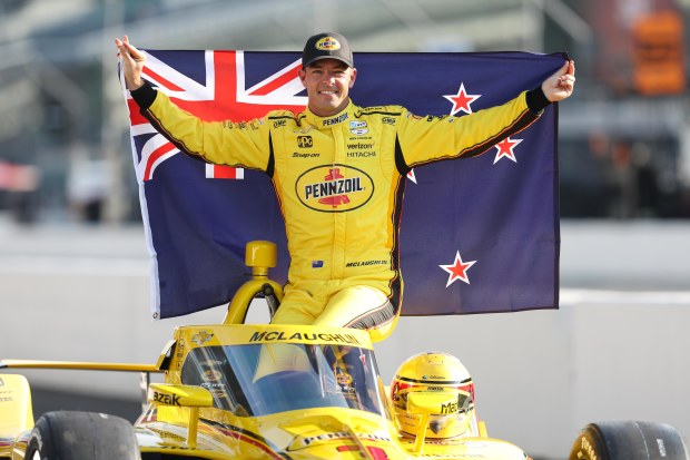 Scott McLaughlin lofts the New Zealand flag after taking pole position for the 2024 Indianapolis 500.