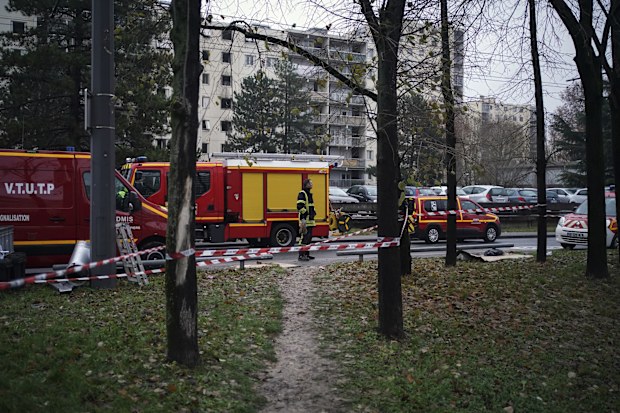 Firefighter stands near ambulance trucks next to apartment buildings seen in background at Le Mas du Taureau neighborhood, in Vauls en Velin, outside Lyon, 