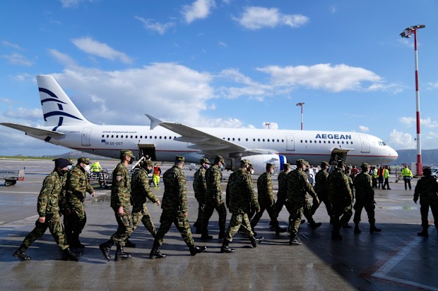 Greek soldiers pass in front of an aircraft, loaded with humanitarian aid at Eleftherios Venizelos International Airport in Athens, on Sunday, Feb. 27, 2022