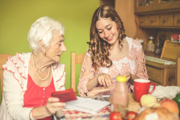 Senior woman at home with younger woman - money, spending, multi generations