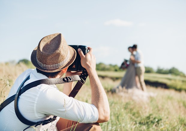 Wedding photographer takes pictures of bride and groom in nature in summer, fine art photo