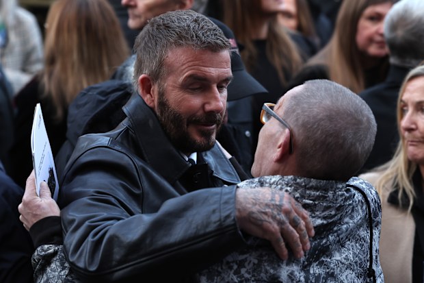 MANCHESTER, ENGLAND - DECEMBER 22:   Greg Mounfield is hugged by Sir David Beckham at the funeral of  his brother Gary Mounfield, also known as Mani, at Manchester Cathedral on December 22, 2025 in Manchester, England. Mani is know for being the bass guitarist in rock bands The Stone Roses and Primal Scream. He died on November 20, 2025 at the age of 63 after suffering from a long-standing lung condition.  (Photo by Ryan Jenkinson/Getty Images)