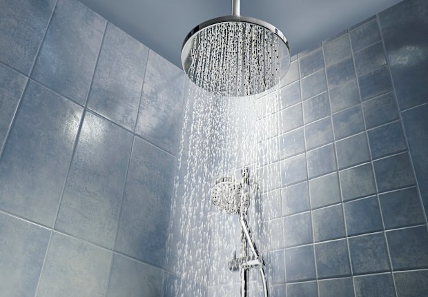 Low angle of running water from shower head in a cool coloured shower.