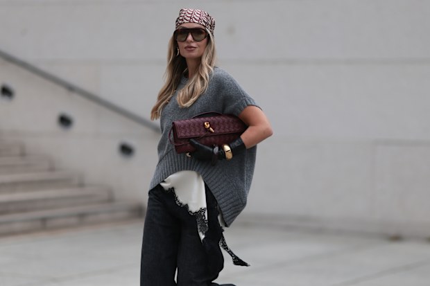 Olga Liber wearing an oversized knit vest over a white satin lace-trim camisole and wide-leg black denim trousers in Berlin, October 2025
