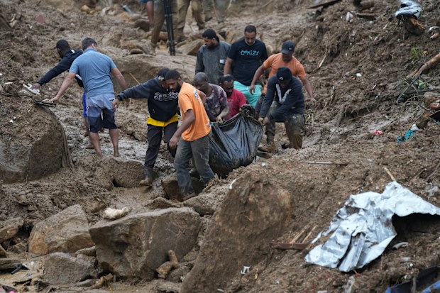 Residents and volunteers remove the body of a landslide victim in Petropolis, Brazil, Wednesday, Feb. 16, 2022. 