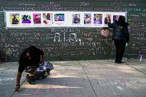 People pay their respects at a makeshift memorial near the scene of Saturday's shooting at a supermarket, in Buffalo, Thursday, May 19, 2022. 