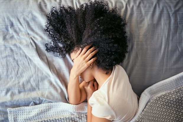 Shot of a young woman suffering from depression in her bedroom